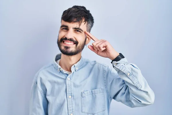 Молодий Іспаномовний Чоловік Бородою Стоїть Над Синім Тлом Посміхаючись Вказуючи — стокове фото