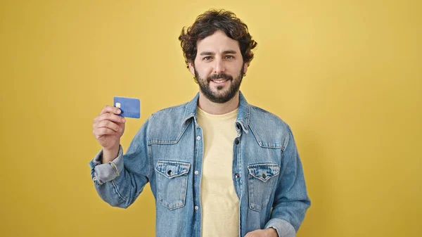 Jovem Hispânico Segurando Cartão Crédito Sobre Fundo Amarelo Isolado — Fotografia de Stock