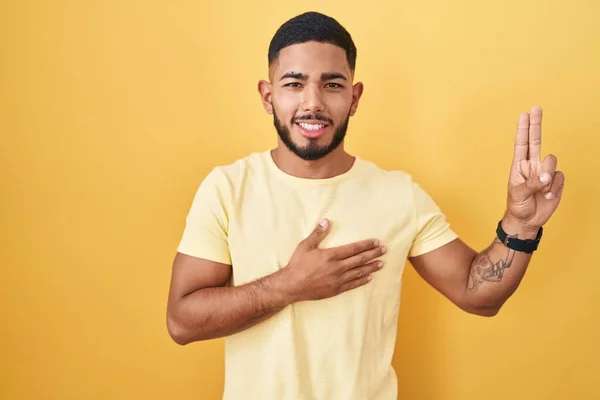 Young Hispanic Man Standing Yellow Background Smiling Swearing Hand Chest — Stock Photo, Image
