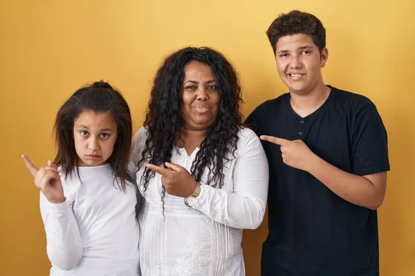 黄色の背景の上に立っている母親 息子の家族は心配し 額で緊張し 心配し 驚きの表情 — ストック写真