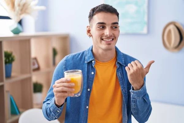 Hombre Hispano Guapo Bebiendo Vaso Jugo Naranja Apuntando Con Pulgar — Foto de Stock