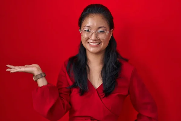 Asiatisk Ung Kvinna Står Över Röd Bakgrund Ler Glad Presentera — Stockfoto