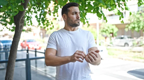 Latin kökenli genç adam ciddi bir ifadeyle sokağa bakıyor.