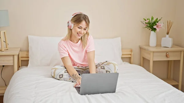 Молода Блондинка Використовує Ноутбук Навушники Сидячи Ліжку Спальні — стокове фото