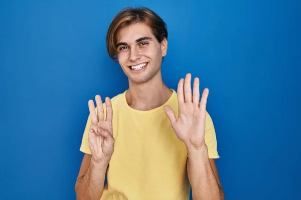 Mavi Arka Planda Duran Genç Adam Sekiz Numaralı Parmaklarını Gösterip — Stok fotoğraf