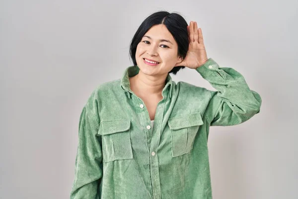 Mladá Asiatka Stojí Nad Bílým Pozadím Usmívá Rukou Uchem Poslouchá — Stock fotografie