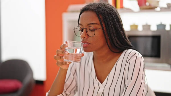 非洲裔美国妇女坐在饭厅的桌上喝水 — 图库照片
