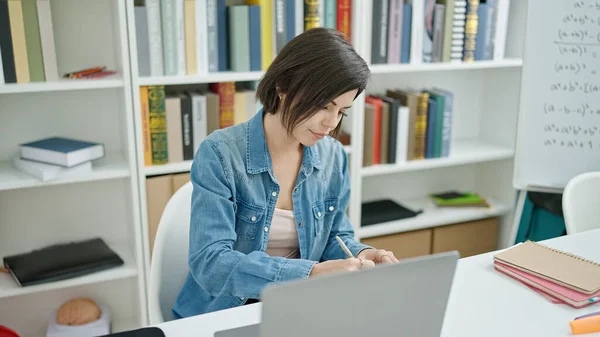 大学の教室でノートパソコンを使ってノートを書く若い白人女性学生 — ストック写真