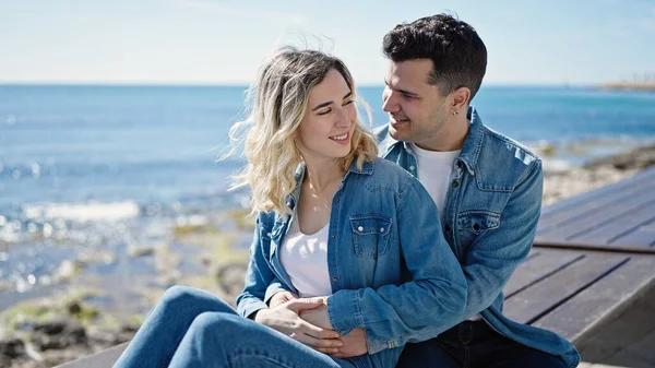 男と女のカップル抱擁お互いに座っていますベンチに海辺で — ストック写真