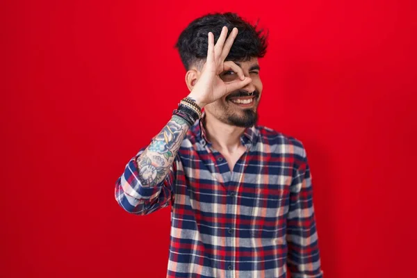 Kırmızı Arka Planda Sakallı Genç Spanyol Bir Adam Hareketleriyle Gülümsüyor — Stok fotoğraf