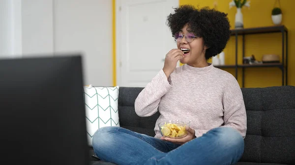 Jovem Afro Americana Assistindo Sentado Sofá Comendo Batatas Fritas Casa — Fotografia de Stock