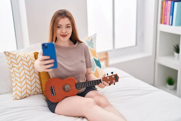 Νεαρή Κοκκινομάλλα Κάνει Selfie Από Smarthone Κρατώντας Ukulele Στο Υπνοδωμάτιο — Φωτογραφία Αρχείου