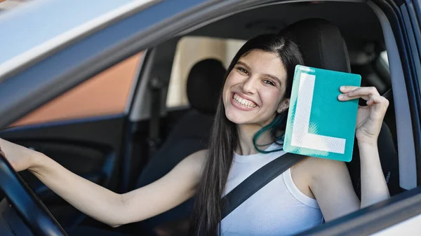 若い美しいヒスパニック系の女性が路上で新しいドライバのライセンスを保持車の上に座って — ストック写真