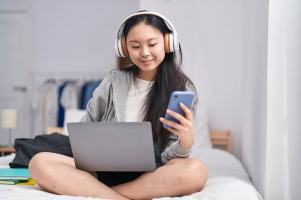 若い中国人女性は寝室でスマートフォンを使用して音楽を聴く — ストック写真