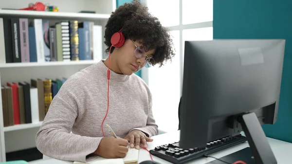 在大学课堂上使用计算机在笔记本上写字的年轻非洲裔美国女学生 — 图库照片