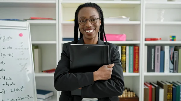アフリカ系アメリカ人の女性教師が大学の教室で自信を持ってフォルダを保持笑顔 — ストック写真