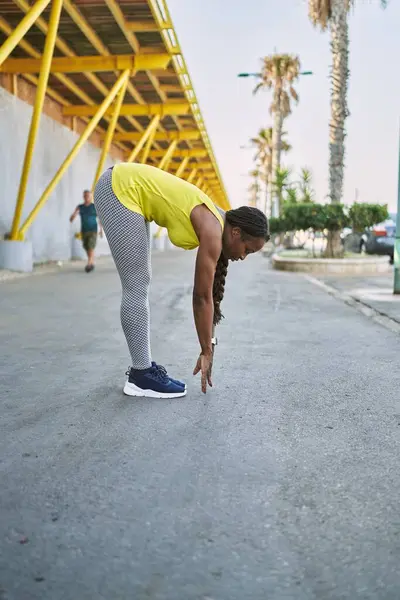 穿着运动服在街上伸腿的非裔美国妇女 — 图库照片