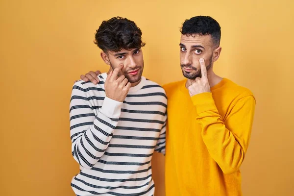 Young Hispanic Gay Couple Standing Yellow Background Pointing Eye Watching — Stock Photo, Image