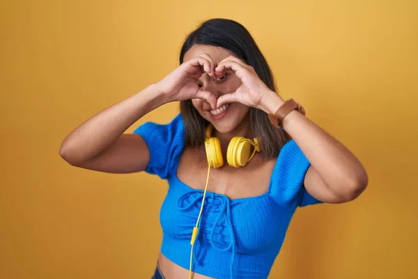 Mujer Joven Hispana Pie Sobre Fondo Amarillo Haciendo Forma Corazón —  Fotos de Stock
