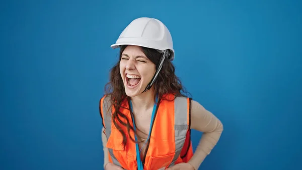惊慌失措的女建筑工人微笑着 自信地站在孤立的蓝色背景之上 — 图库照片