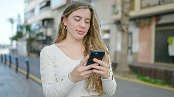 Νεαρή Ξανθιά Γυναίκα Που Χρησιμοποιεί Smartphone Σοβαρή Έκφραση Στο Δρόμο — Φωτογραφία Αρχείου