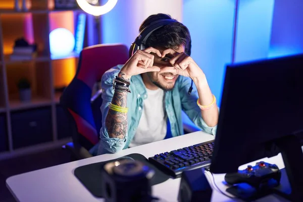 stock image Young hispanic man streamer smiling confident doing heart symbol with hands at gaming room