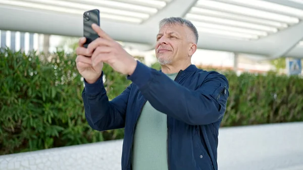 中年白发男人在公园用智能手机自信地笑着自拍 — 图库照片
