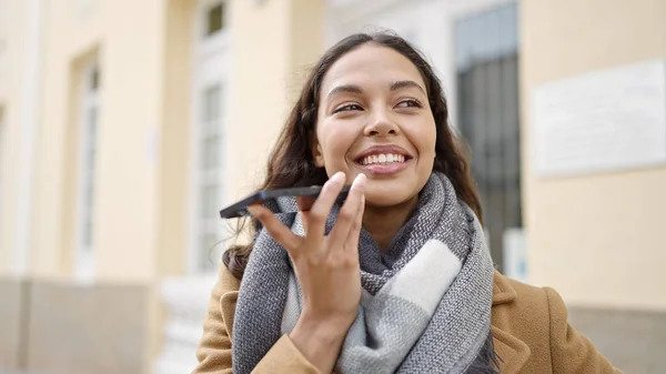 若い美しいですヒスパニック女性送信音声メッセージとともにスマートフォンでストリート — ストック写真