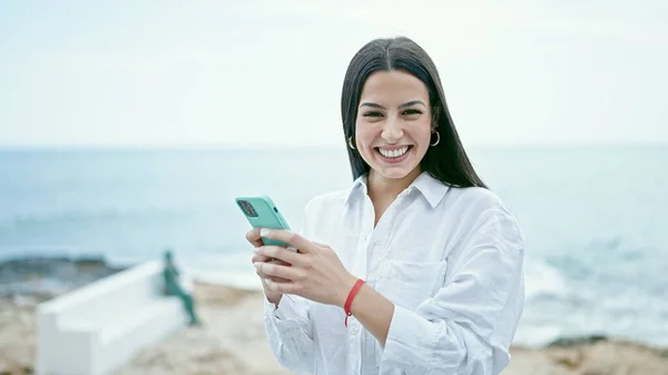Młoda Piękna Latynoska Kobieta Pomocą Smartfona Uśmiechnięta Nad Morzem — Zdjęcie stockowe