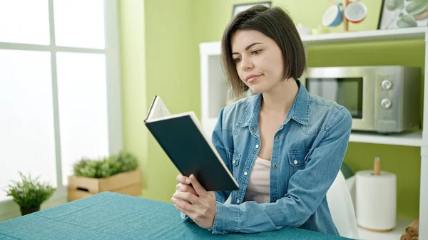 Νεαρή Καυκάσια Γυναίκα Διαβάζει Βιβλίο Κάθεται Στο Τραπέζι Στο Σπίτι — Φωτογραφία Αρχείου