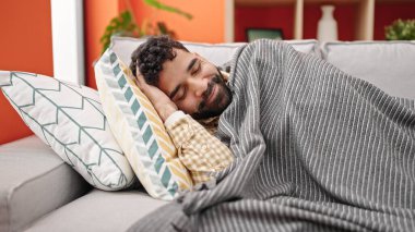 Genç İspanyol adam kanepede uzanıyor.