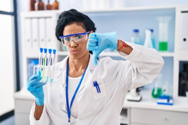 Orta yaşlı İspanyol kadın kızgın yüzlü bilim adamı laboratuvarında çalışıyor. Negatif işaretler baş parmakları aşağıda, reddedilme konsepti ise... 