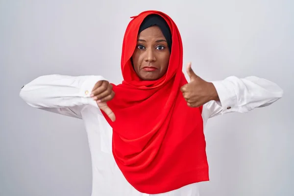 伝統的なイスラム教のヒジャーブスカーフを身に着けている若いアラブ女性は 親指を上下に 意見の相違や合意表現を行います 狂気の葛藤 — ストック写真