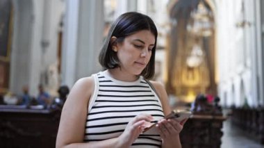 Viyana 'daki Augustinian Kilisesi' nde akıllı telefon kullanarak kiliseyi ziyaret eden güzel İspanyol bir kadın.
