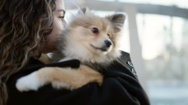 Parkta yüzünde ciddi bir ifadeyle duran köpekli genç İspanyol kadın.
