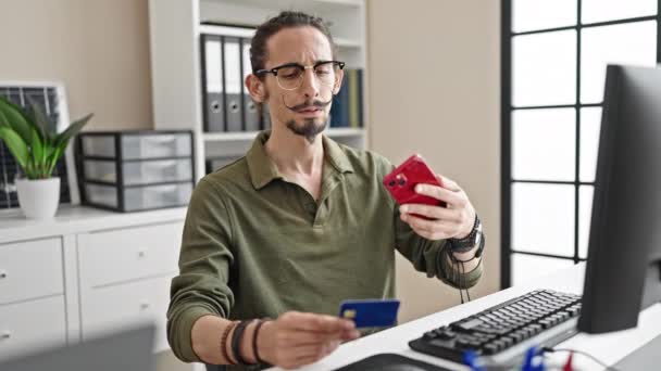 若いヒスパニック男性ビジネスワーカーは オフィスでスマートフォンでクレジットカードに写真を作ります — ストック動画