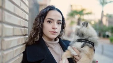 Köpeğiyle gülümseyen, sokakta kendine güvenen genç İspanyol kadın.