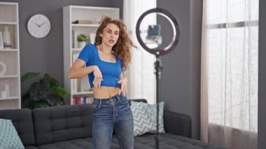 Genç bir kadın evde dans dersi kaydı yapıyor.