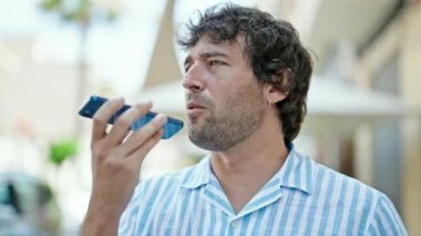 Genç İspanyol adam sokakta akıllı telefonuyla sesli mesaj yolluyor.