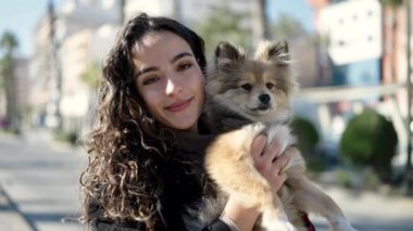 Köpeğiyle gülümseyen, sokakta kendine güvenen genç İspanyol kadın.