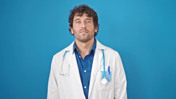 年轻的惊慌失措的男医生 手托着胸膛在孤零零的蓝色背景下宣誓 — 图库视频影像