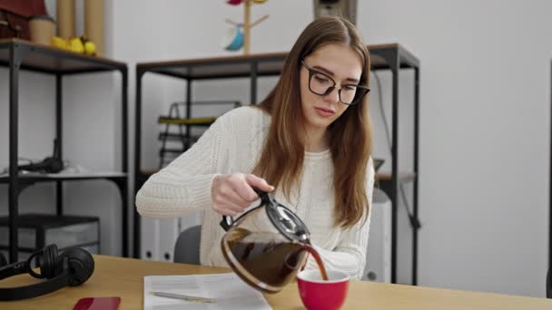若いヒスパニック系の女性のビジネスワーカーがオフィスでカップにコーヒーを注ぐ — ストック動画