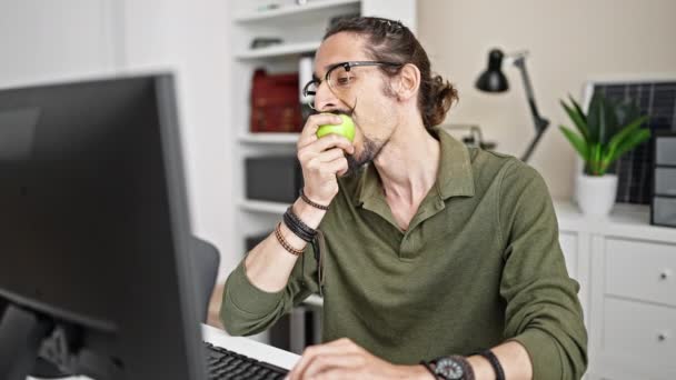 Νέος Ισπανόφωνος Επιχειρηματίας Που Χρησιμοποιεί Υπολογιστή Τρώγοντας Μήλο Στο Γραφείο — Αρχείο Βίντεο