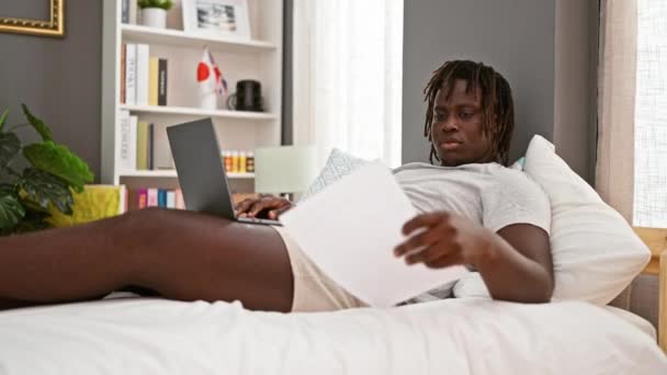 Afro Amerikaanse Man Met Behulp Van Laptop Leesdocument Liggend Bed — Stockvideo