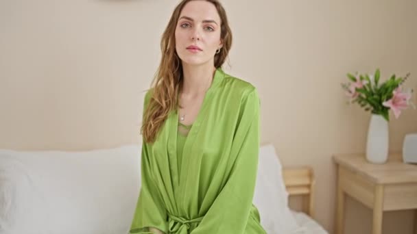 Mujer Rubia Joven Sentada Cama Con Cara Seria Dormitorio — Vídeo de stock
