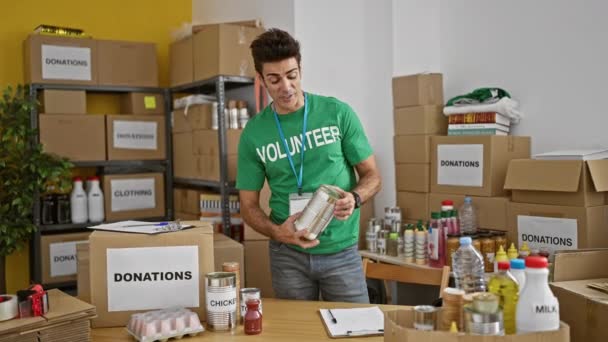 Joven Hispano Voluntario Sosteniendo Productos Hablando Centro Caridad — Vídeo de stock