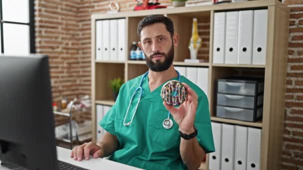 Joven Médico Hispano Sosteniendo Donut Haciendo Gesto Pulgar Hacia Abajo — Vídeos de Stock
