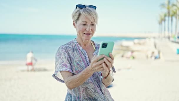 Блондинка Середнього Віку Туристка Посміхається Впевнено Використовуючи Смартфон Пляжі — стокове відео