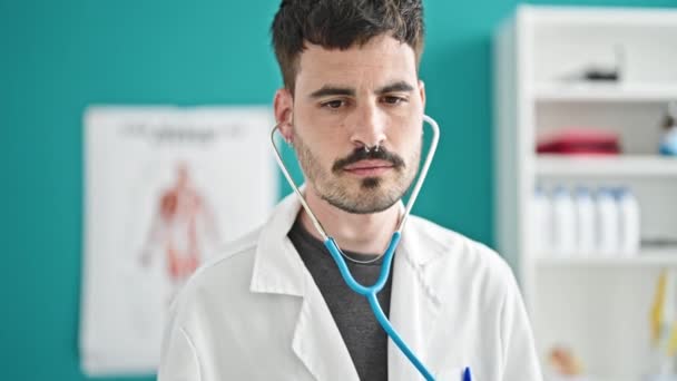 Ung Latinamerikansk Man Läkare Ler Säker Undersöka Med Stetoskop Kliniken — Stockvideo