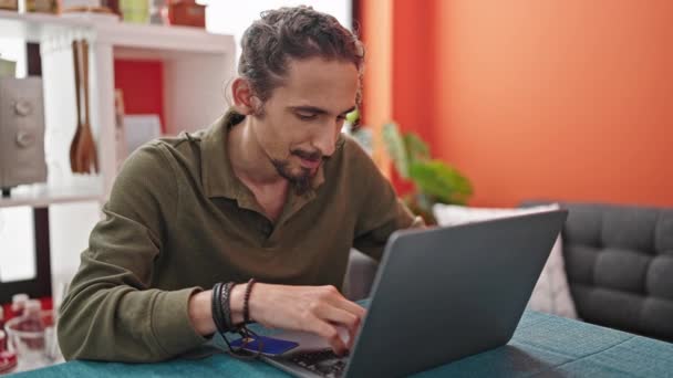 Молодий Іспаномовний Чоловік Купує Ноутбуком Кредитною Карткою Сидячи Столі Їдальні — стокове відео